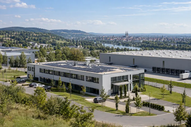 Moderne Büro- und Logistikgebäude am Rand von Regensburg, im Hintergrund hügelige Landschaft und die Domtürme