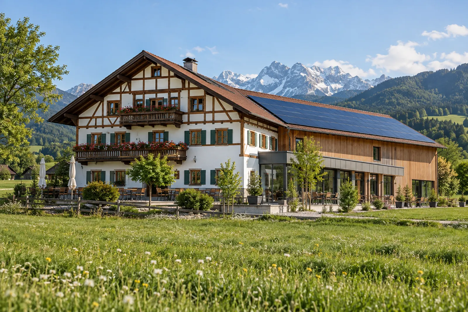 Sanierter Gewerbebau mit Photovoltaik-Dach vor Alpenkulisse in Oberbayern