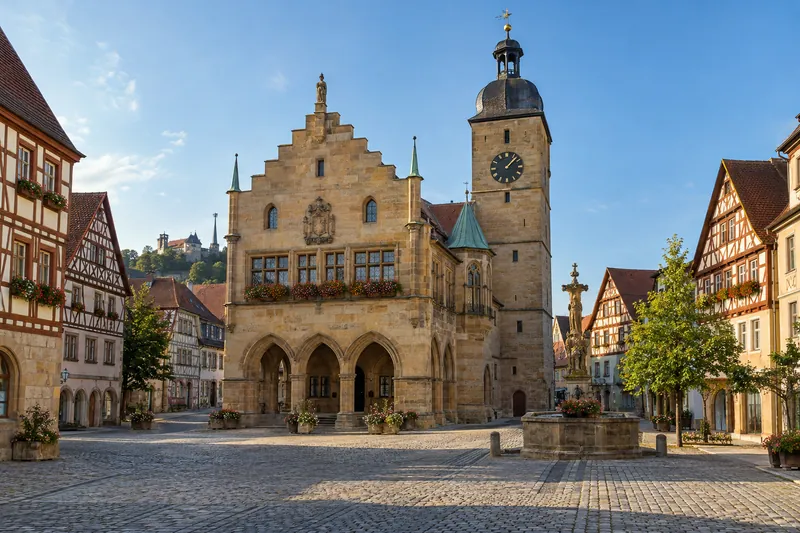 Historisches Rathaus mit Stufengiebel und Uhrturm an einem Marktplatz mit Kopfsteinpflaster in einer fränkischen Altstadt