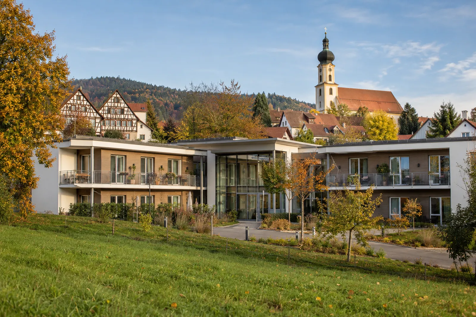 Zweigeschossiges Pflegeheim mit Balkonen in einer bayerischen Kleinstadt, dahinter Fachwerkhäuser und ein Kirchturm