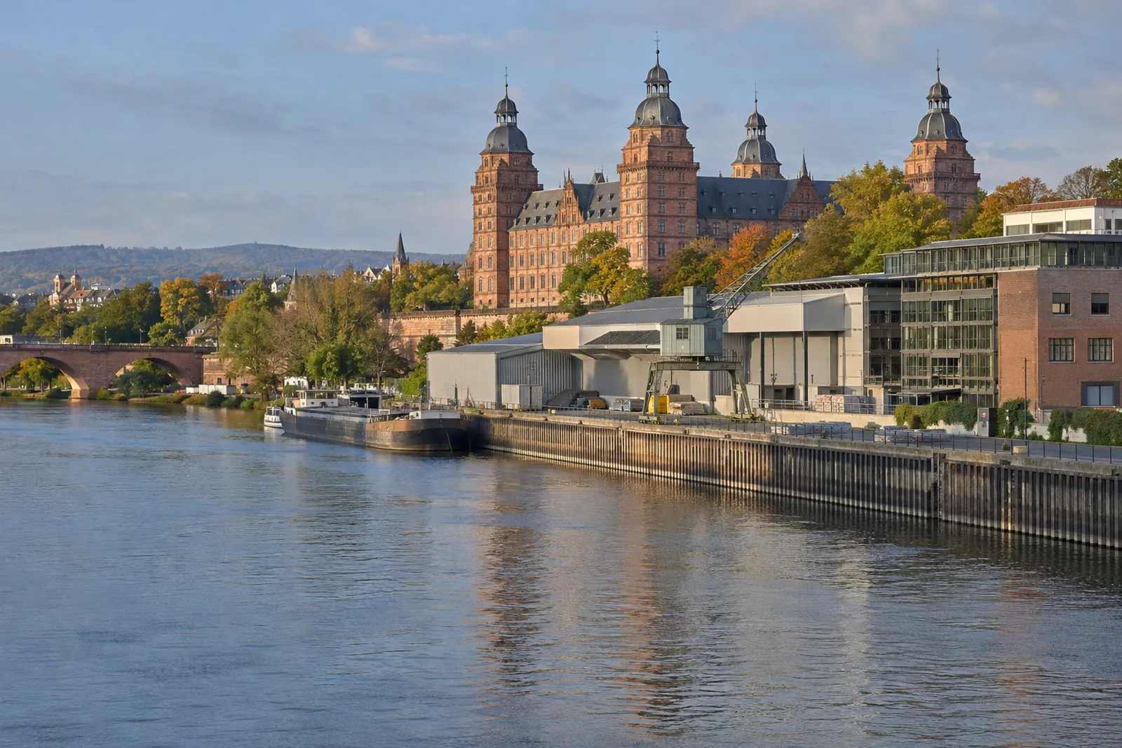 Rotes Renaissance-Schloss am Main in Aschaffenburg mit Gewerbebauten und Lagerhallen im Vordergrund