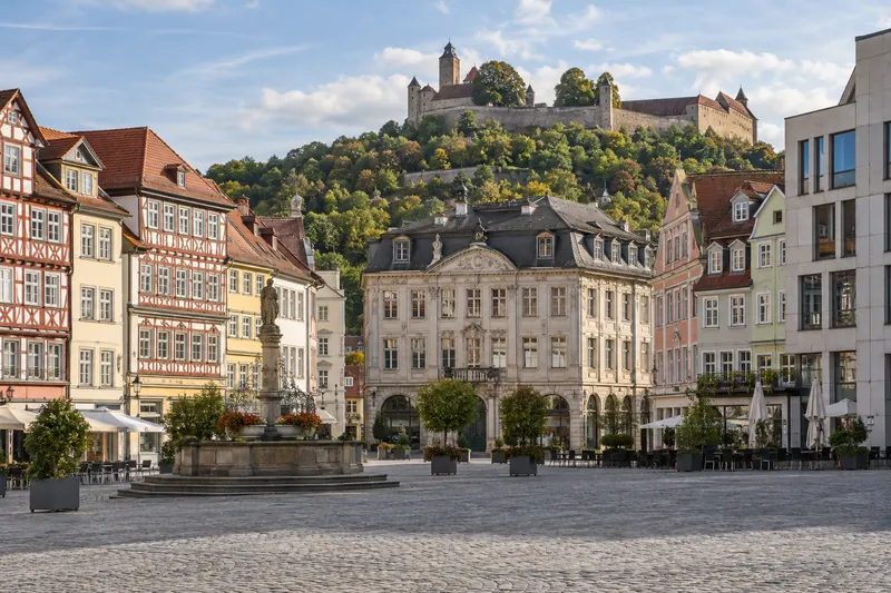 Geschäftshäuser rund um den Coburger Marktplatz, im Hintergrund die Veste Coburg auf dem Hügel