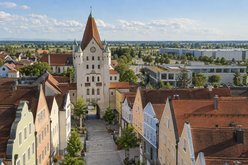 Stadttor in der Erdinger Altstadt, dahinter Gewerbebauten im flachen Land des Erdinger Mooses