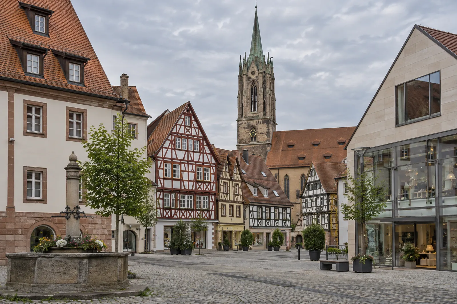 Altstadt mit Fachwerk- und Geschäftshäusern, im Hintergrund ein Kirchturm, im Vordergrund ein moderner Gewerbebau