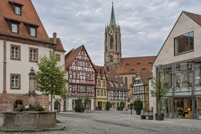 Altstadt mit Fachwerk- und Geschäftshäusern, im Hintergrund ein Kirchturm, im Vordergrund ein moderner Gewerbebau